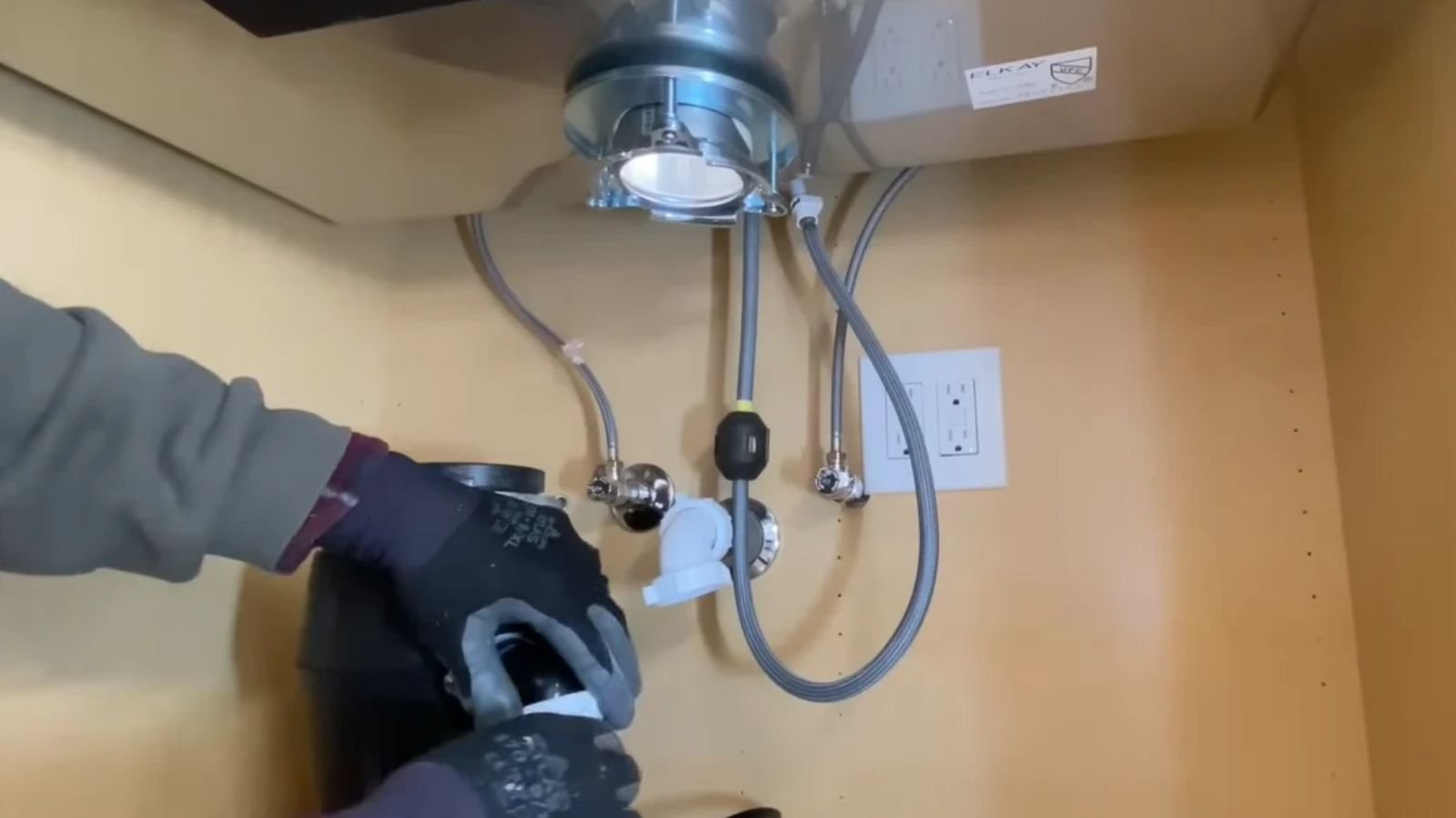 Garbage disposal unit being installed under a kitchen sink in Naples, FL